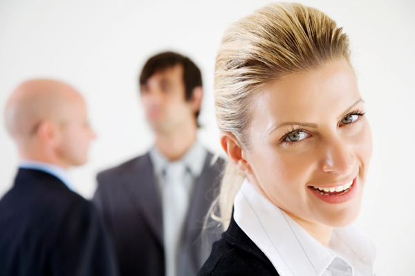 smiling professional woman with suited men in background